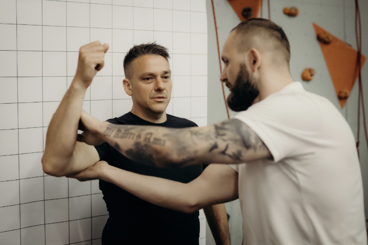 Tomek sprawdza ruchomość ramienia u podopiecznego przy ścianie